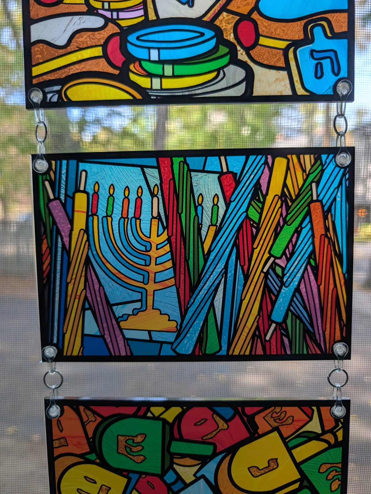 stained glass style decoration with hanukah candles and a menorah in the background