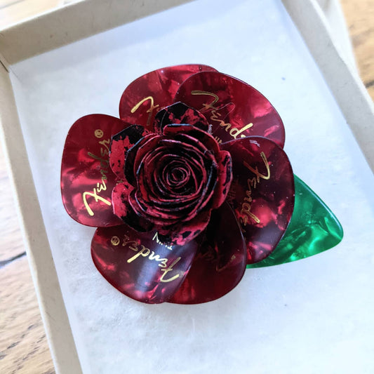 Red boutonniere made from guitar picks in a box.