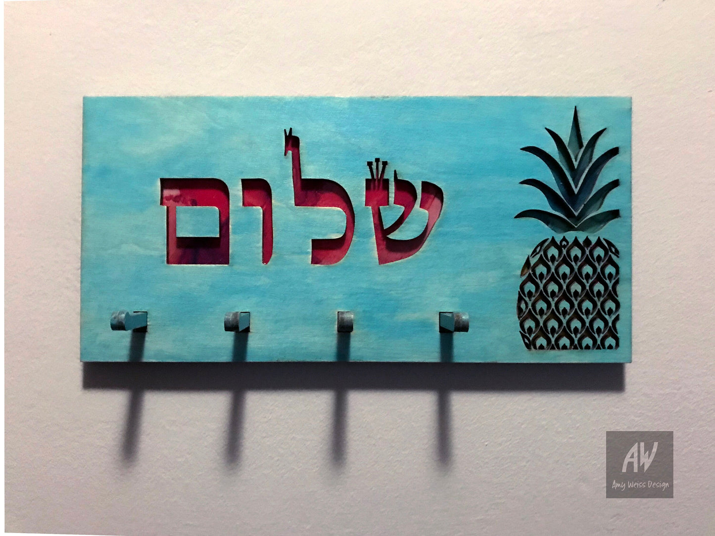 Blue stained wood keyholder with hebrew cutout letters "Shalom", 4 pegs for keys, and a pineapple.
