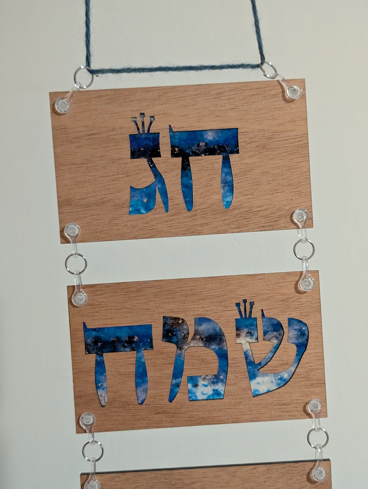 Wooden plaque with blue cut-out letters on a white background